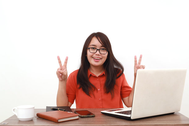 快乐的年轻亚洲企业家坐着做胜利的手势。孤立于白色图片下载