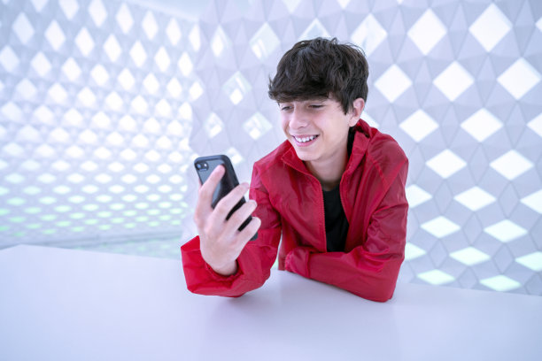 一个像数字游牧民一样的青少年在奥斯陆歌剧院里用他的智能手机进行视频通话。你所处的环境就像宇宙飞船一样图片下载