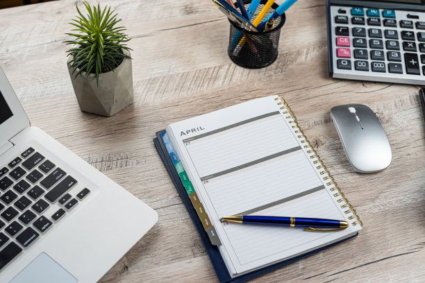 笔记本电脑的俯视图，笔记本笔计算器花在办公桌上图片下载