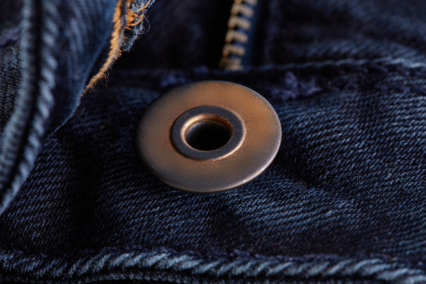 牛仔牛仔裤的纹理背景与撕裂。彩色棉织物的质地。缝制纹理牛仔裤背景。时尚牛仔裤纽扣。牛仔裤上的口袋和铆钉。纤维和织物结构。图片下载