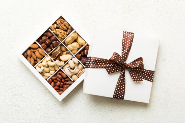 桌子背景的纸盒里放着各种各样的坚果。前视图。健康食品。近景，复制空间，俯视图，平铺。核桃，开心果，杏仁，榛子和腰果图片下载