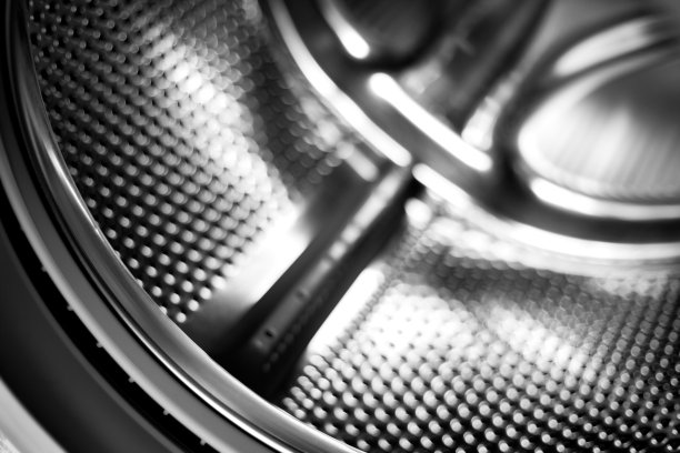 洗衣机滚筒内部。用于自动洗衣机的穿孔不锈钢滚筒。黑色和白色，金属背景图片下载