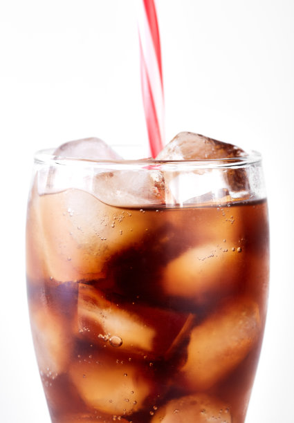 可乐装在玻璃杯里，白色背景上有吸管和冰块。苏打水与气泡隔离在白色上。清爽的无酒精饮料图片下载