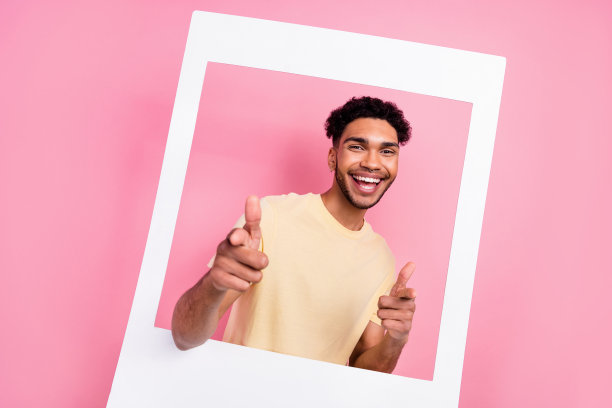 漂亮英俊的男人的肖像，非洲发型，穿着黄色t恤，直接从相框上孤立的粉红色背景图片下载