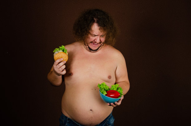 饮食和营养不良。滑稽的胖子在摄影棚里摆姿势。图片下载