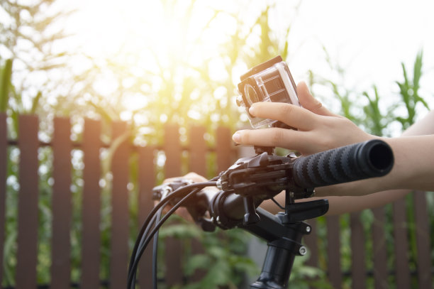 一位女士的手在调整安装在山地车车把上的数码相机。图片下载