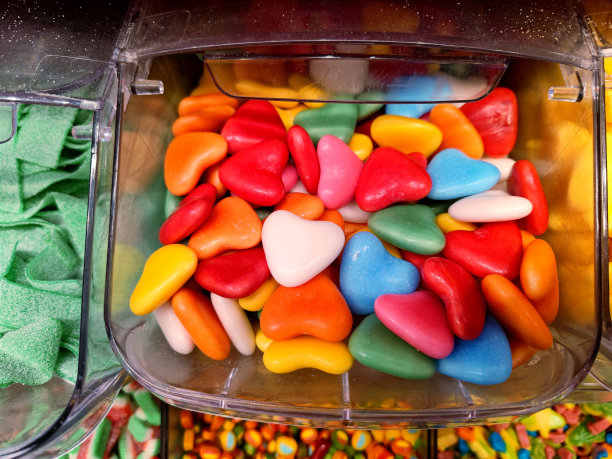 糖果店货架上不同颜色的心形糖果的特写镜头，顾客可以自己挖糖果图片下载