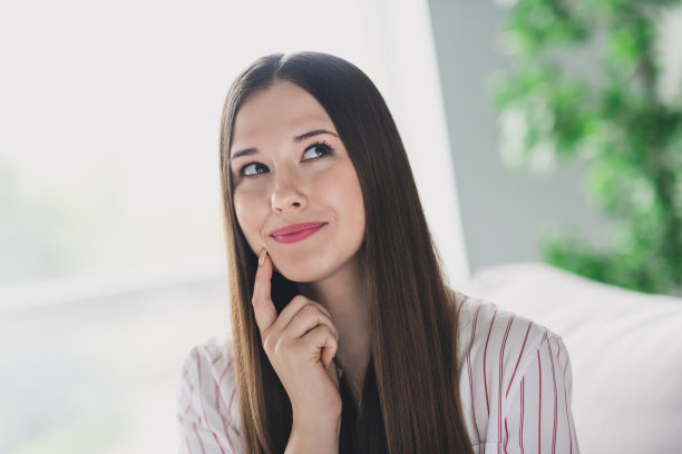 可爱狡猾狡猾的年轻女孩穿着条纹衬衫，手指脸颊颧骨计划在室内公寓房间图片下载