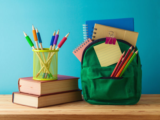 蓝色背景的木桌上有背包、铅笔和书，这是返校的概念图片下载