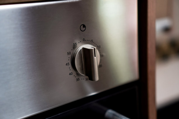 厨房墙壁上安装的电烤箱的定时器调节旋钮特写。图片下载