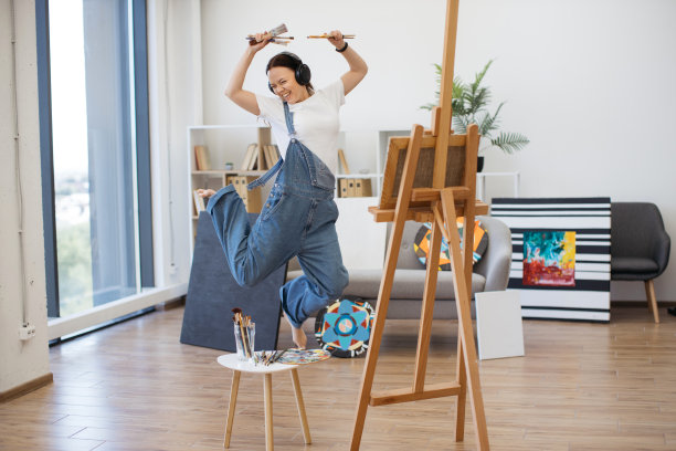 拿着画笔和耳机在空中跳跃的艺术家图片下载