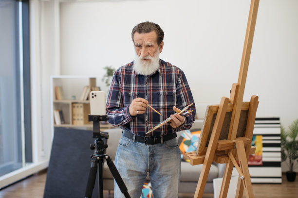 拿着画笔的调色板对着镜头说话的退休者图片下载