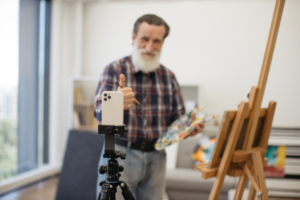 退休男子在工作室用智能手机录制视频图片下载