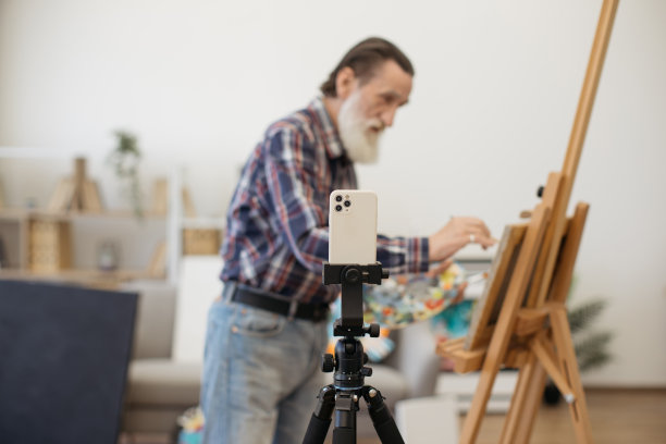 灰胡子艺术家在室内用智能手机录制视频图片下载