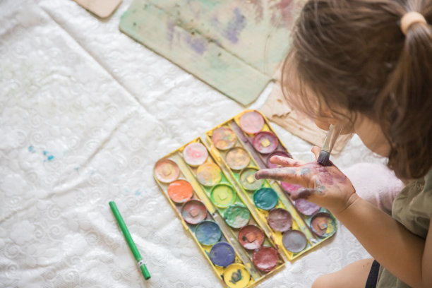 可爱的小女孩在玩颜料。孩子在家庭环境中用水彩画探索他的创造力。图片下载