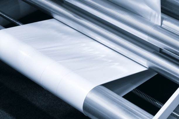 适用于产品、食品塑料包装的光效全自动工业机械。轴上的自动包装线用塑料薄膜呈现浅蓝色景象。产品包装理念图片下载