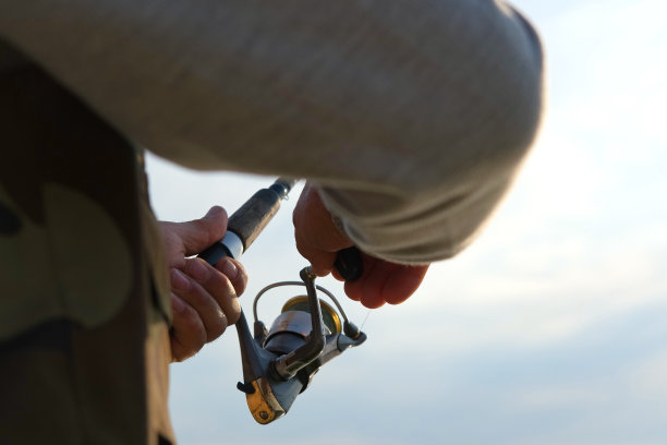 老人钓鱼。夕阳西下，一位白发苍苍的老渔夫从码头上抛下一缕丝线。积极的老年男性在湖中垂钓，旋转卷轴杆。退休渔民享受他的周末图片下载