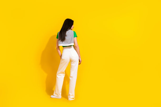 照片中性感苗条的女士穿着绿色t恤微笑摆姿势，背部空白，孤立的黄色背景图片下载