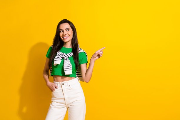 照片中酷炫的潮女孩穿着时髦的街头服装，直接用手指空着空间购物，提供孤立的黄色背景图片下载