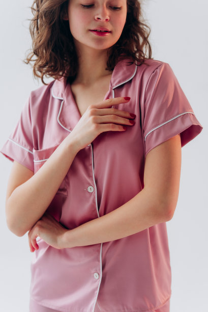 漂亮的年轻女子穿着一件浅灰色的睡衣。卷发模特女郎图片下载