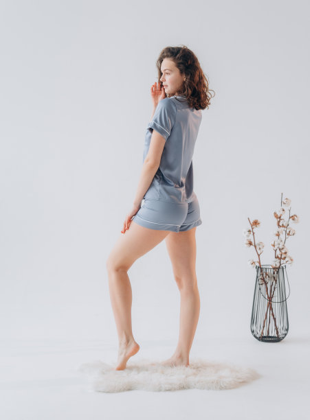 穿着白色背景的蓝色睡衣、短裤和衬衫的年轻女子图片下载