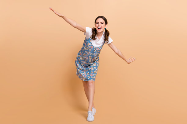 小女孩的全身照片穿着夏装潮流服装飞翼手臂轻盈的感觉随意孤立在米色背景图片下载