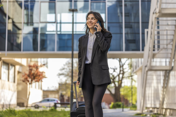 时尚的商务女性在出差时提着行李箱，接到了一个有趣的电话图片下载