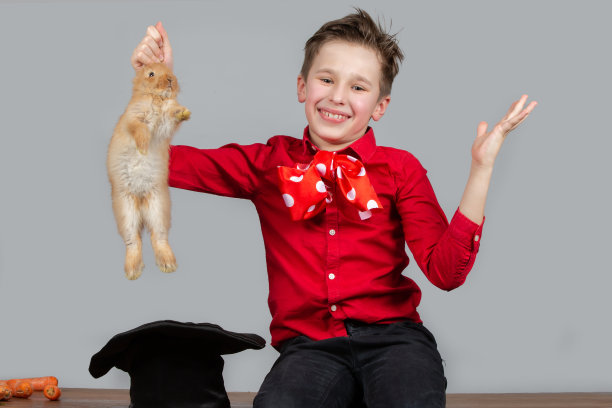 魔术师男孩从帽子里拿出兔子。图片下载