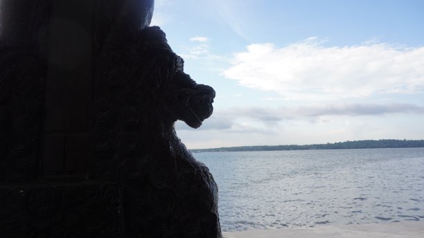 龙头雕像的剪影高于海水与岛屿和清澈的蓝天背景图片下载