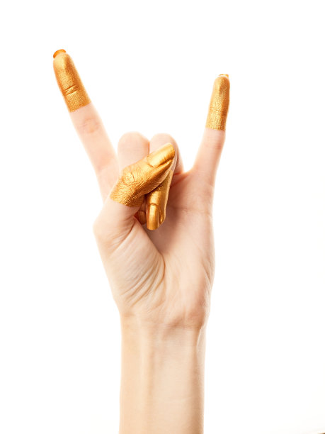 双手涂上金色的颜料。金手指。女性的手被孤立在白色背景上。白人女性放松的手显示符号和手势。图片下载