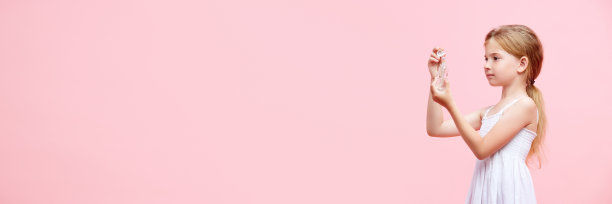 小女孩，孩子在粉红色的工作室背景下涂抹面部精华液，护理皮肤图片下载