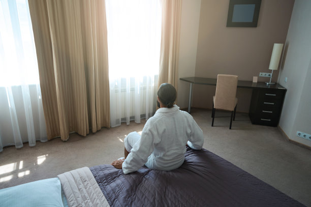 成年男子坐在舒适的卧室里的大床上图片下载