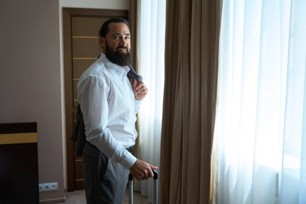 一个威严的中年男子站在旅馆房间的窗口图片下载