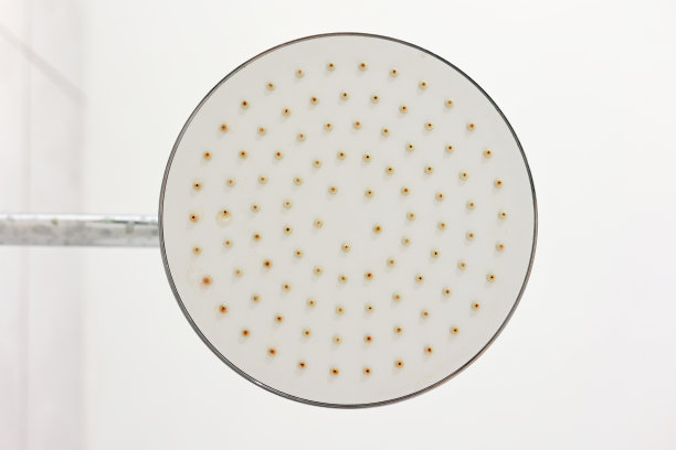 肮脏的钙化圆形淋浴头和淋浴臂，镀铬的龙头，带有铁锈和水垢的水龙头，硬水形成的斑块，特写，底部视图。清洁公司理念。图片下载