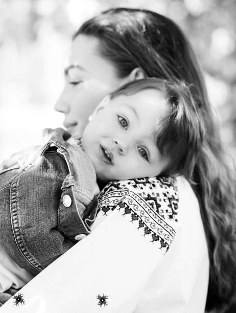 黑白照片小婴儿在妈妈的手上。两个人的家庭肖像。春天风景背景。图片下载