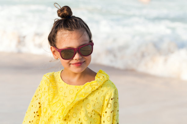 漂亮的微笑的小女孩穿着黄色的裙子和太阳镜图片下载