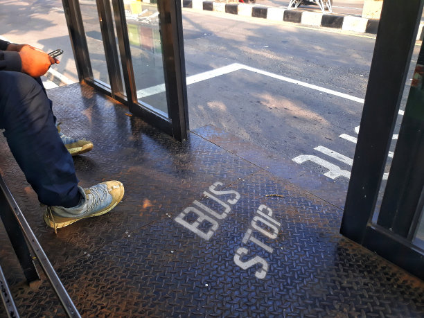 公交车乘客在车站等车时使用手机图片下载