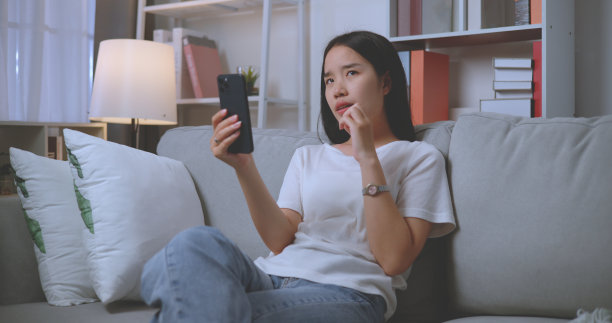 年轻女子在客厅用智能手机自拍图片下载