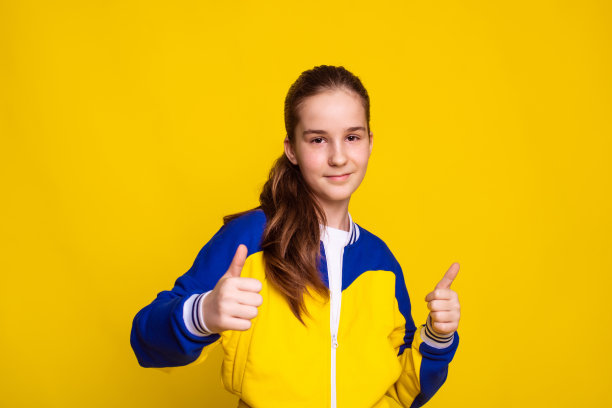 运动器材的促销和销售，黄色背景上女孩竖起大拇指的手势图片下载