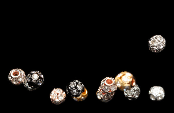 时尚金银珠球，做工精美，细节考究。奢华的银铜金属珠珠亮片球是时尚潮流，在空中飞翔。黑色背景孤立的选择性聚焦模糊图片下载