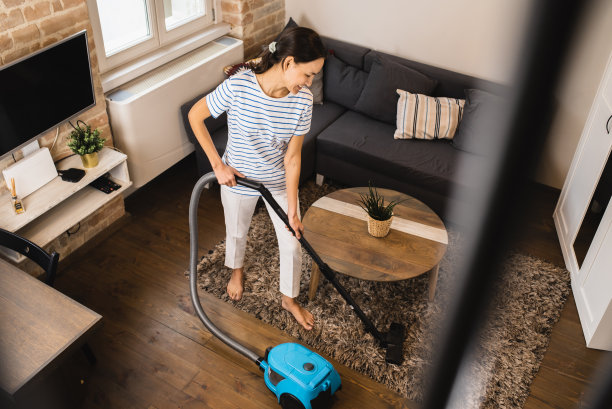 一位女士正在用吸尘器清洁地毯图片下载