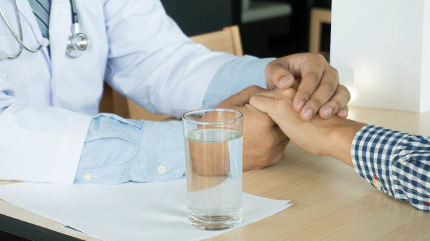 医生的医疗保健。穿着白色制服长袍大衣的专业医生面试咨询病人，安慰他的男病人伸出援助之手图片下载