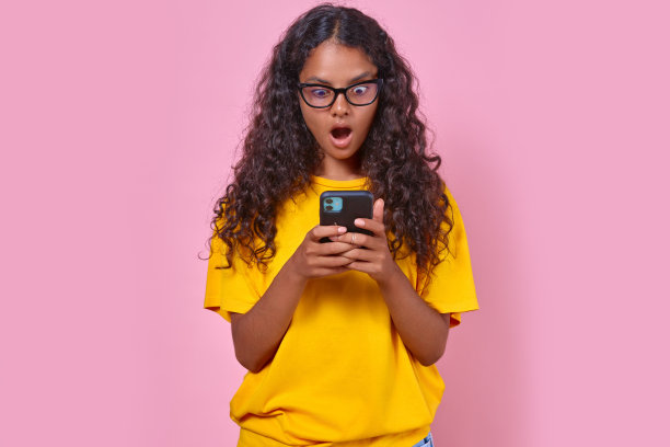 年轻惊讶的印度少女拿着手机站在演播室里图片下载