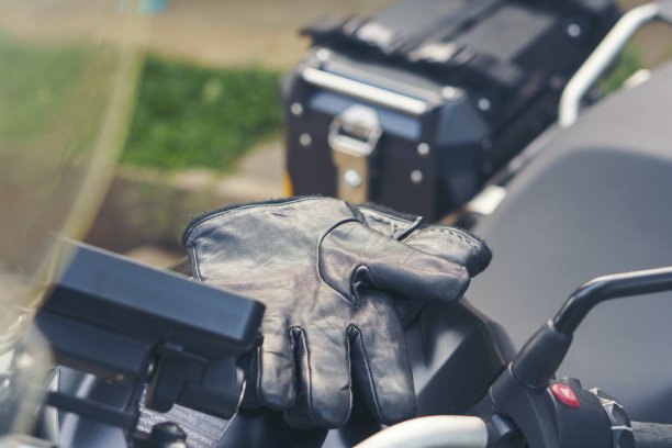 摩托车停车和骑摩托车的人把皮手套放在摩托车上。泰国，年轻的旅行者在高速公路上骑摩托车。摩托车概念的旅行和生活方式。图片下载
