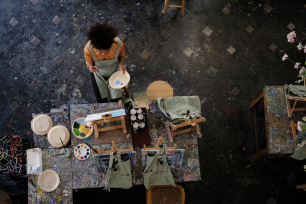 从上面看，才华横溢的女性在艺术教室的画布上作画。艺术，创造性学习和休闲活动的理念。图片下载