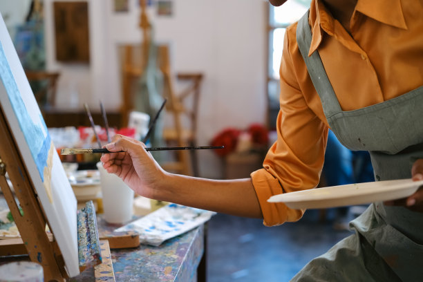 微笑的非裔美国女艺术家创作杰作，在艺术工作室用毛笔在画布上作画。图片下载