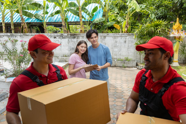 一对年轻夫妇和两个从皮卡车上卸下箱子和家具的搬运工核对图片下载