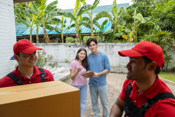 一对年轻夫妇和两个从皮卡车上卸下箱子和家具的搬运工核对图片下载