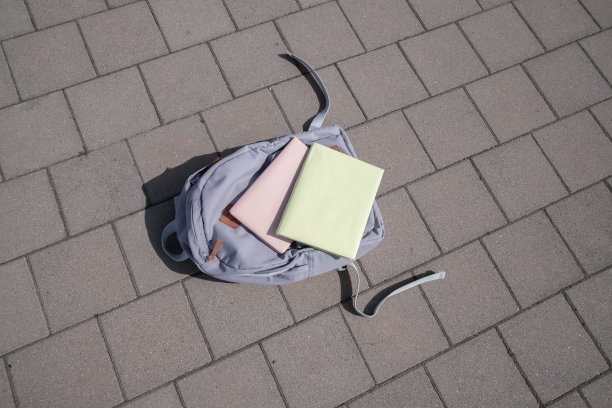 一个装有书的背包躺在外面的地板上。告别学校，毕业，假期的概念图片下载