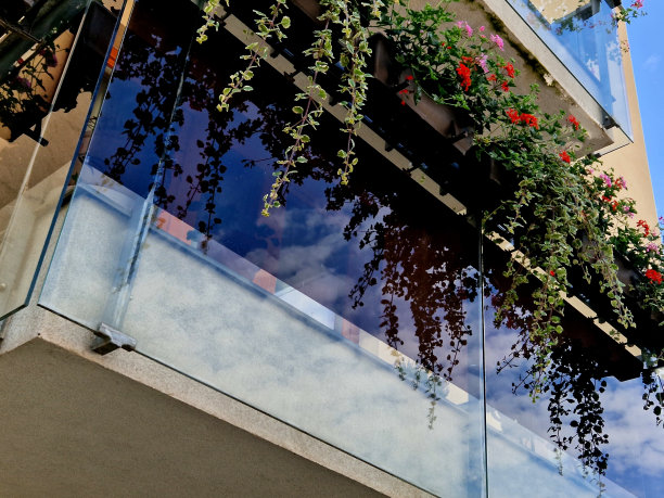 豪华住宅的栏杆，由玻璃面板和金属不锈钢把手固定而成。给人一种轻快的印象。抛光金属盖在温室露台的窗户上，反射图片下载